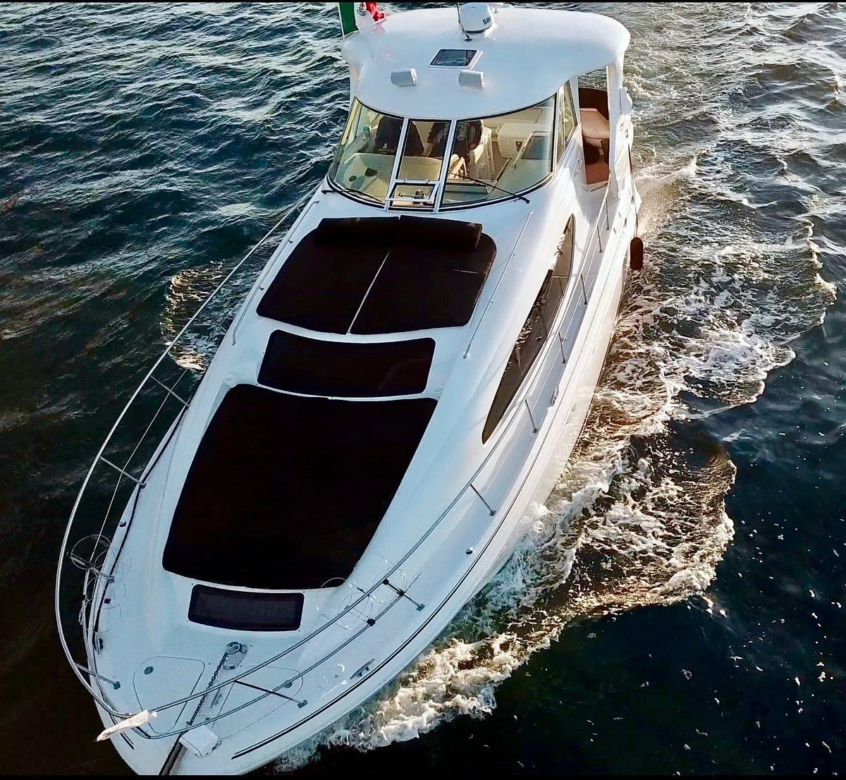 A white yacht sailing on the water, viewed from above.