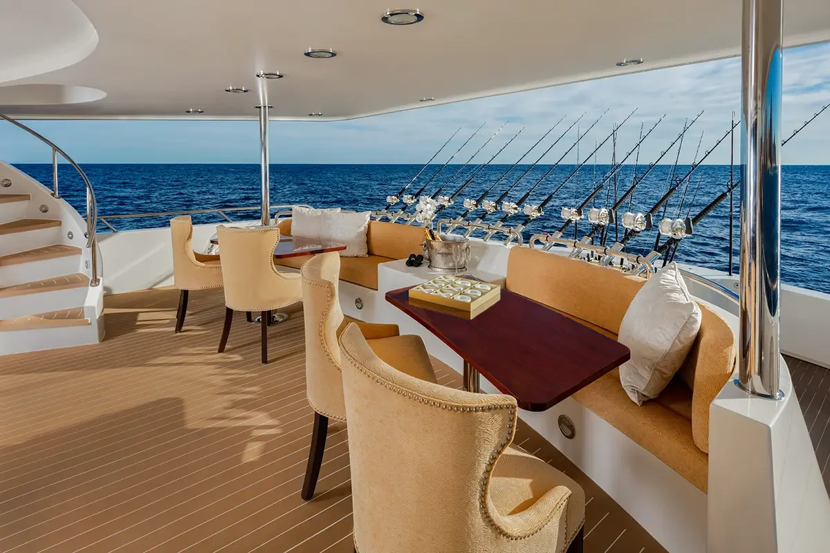 Luxury yacht deck with fishing rods, outdoor seating, and ocean view.