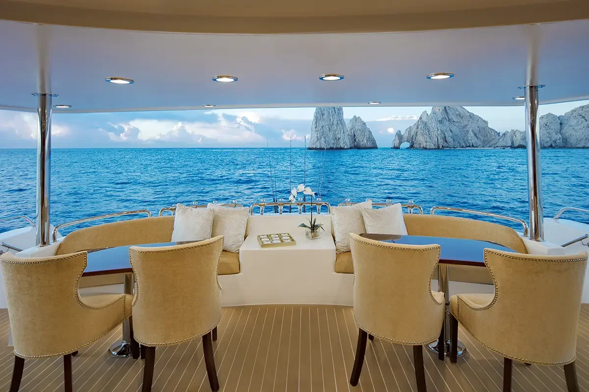 View from the deck of a yacht showing the ocean, rocky islands, and a cloudy sky in the background.