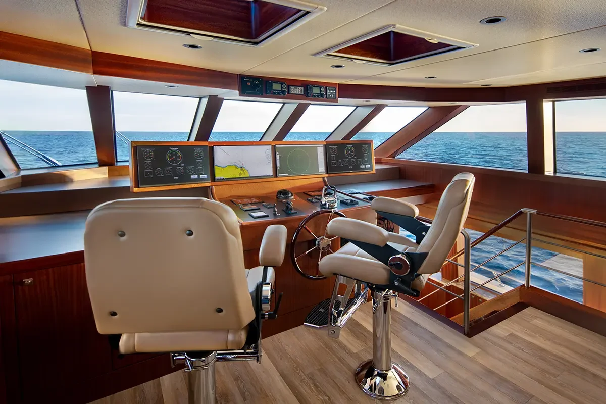 Captain's control room with navigation instruments, steering wheel, and ocean view through windows.