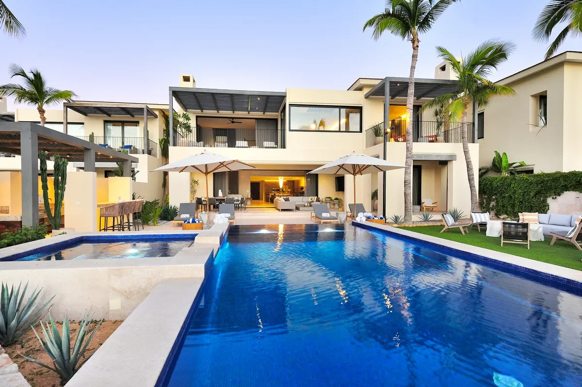 Luxury modern house with a swimming pool, palm trees, and outdoor seating area.
