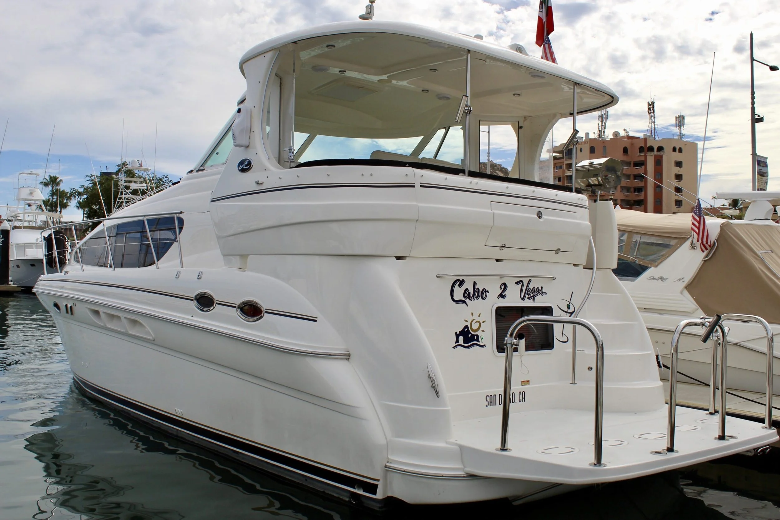 Luxury white yacht docked in a marina with city buildings and cloudy sky in the background