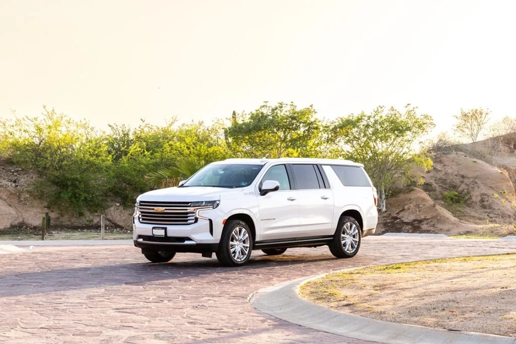 A white SUV parked on a brick road with greenery and hills in the background during daylight.