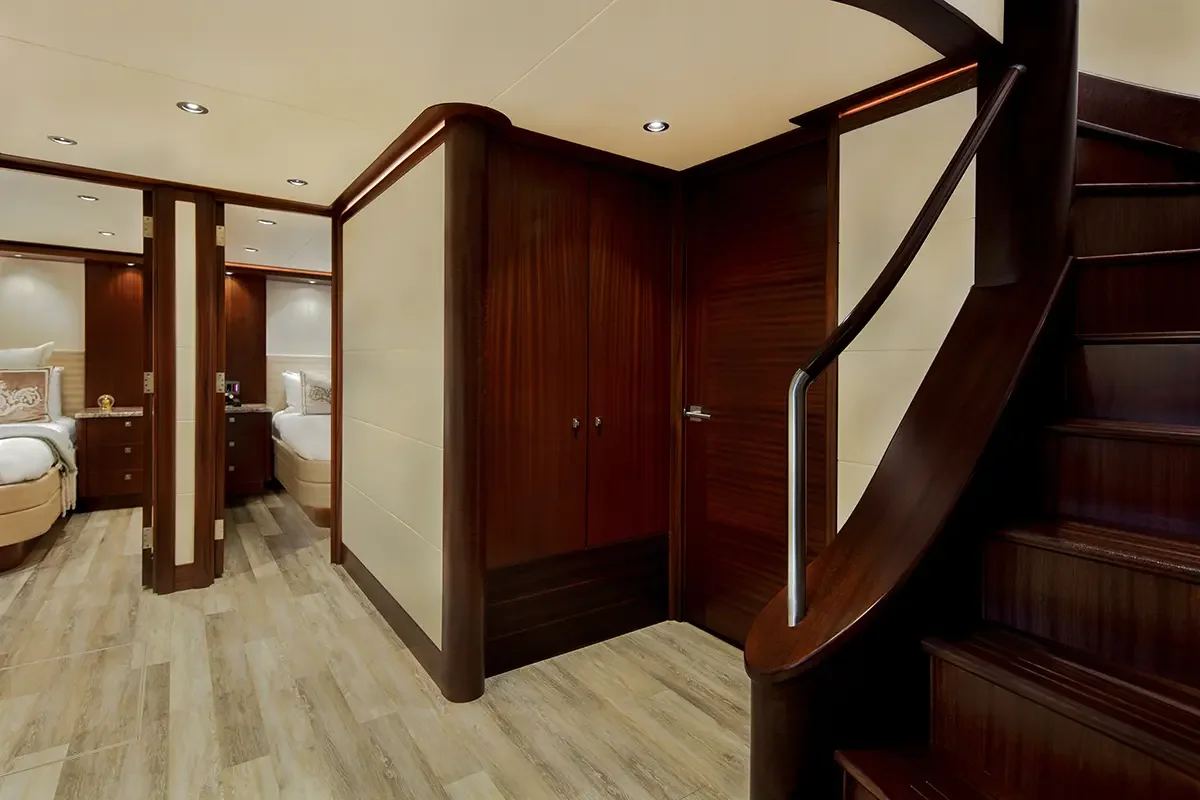 Interior view of a luxury hotel with two beds, wooden headboards, nightstands, and bedside lamps, featuring warm lighting and wooden accents.