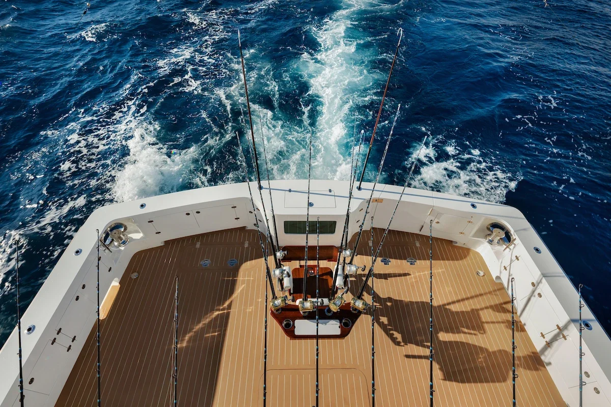 Overhead view of the stern of a boat with fishing rods, looking out over the ocean.