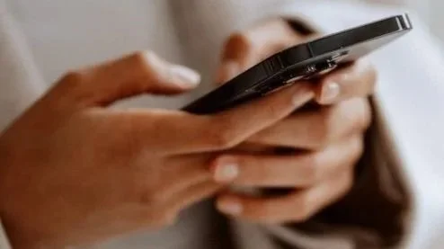 Close-up of person holding and using a smartphone.