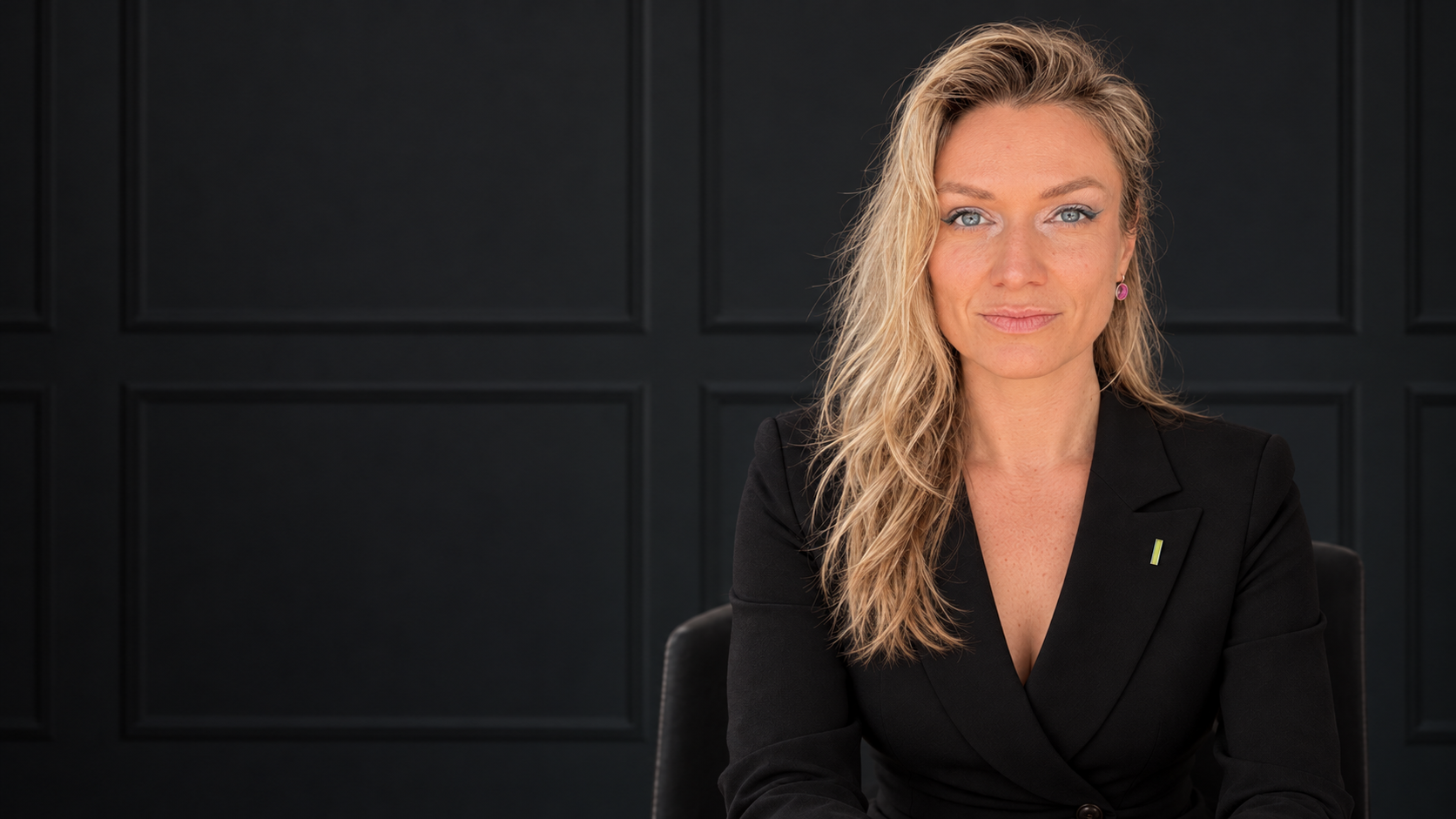 Anna Shilina in a black blazer against a black panelled wall.