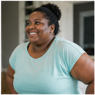 A smiling Black woman with curly hair tied up, wearing a light blue T-shirt.