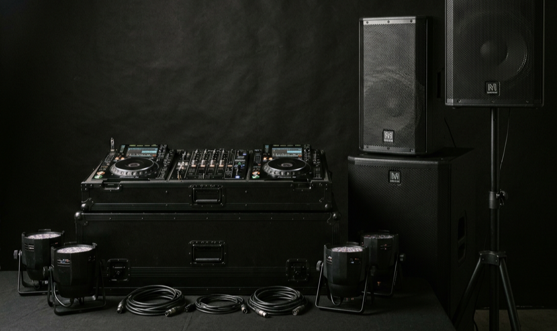 DJ equipment setup with two CDJ turntables, a mixer, martin speakers on stands, and various cables on a black background.