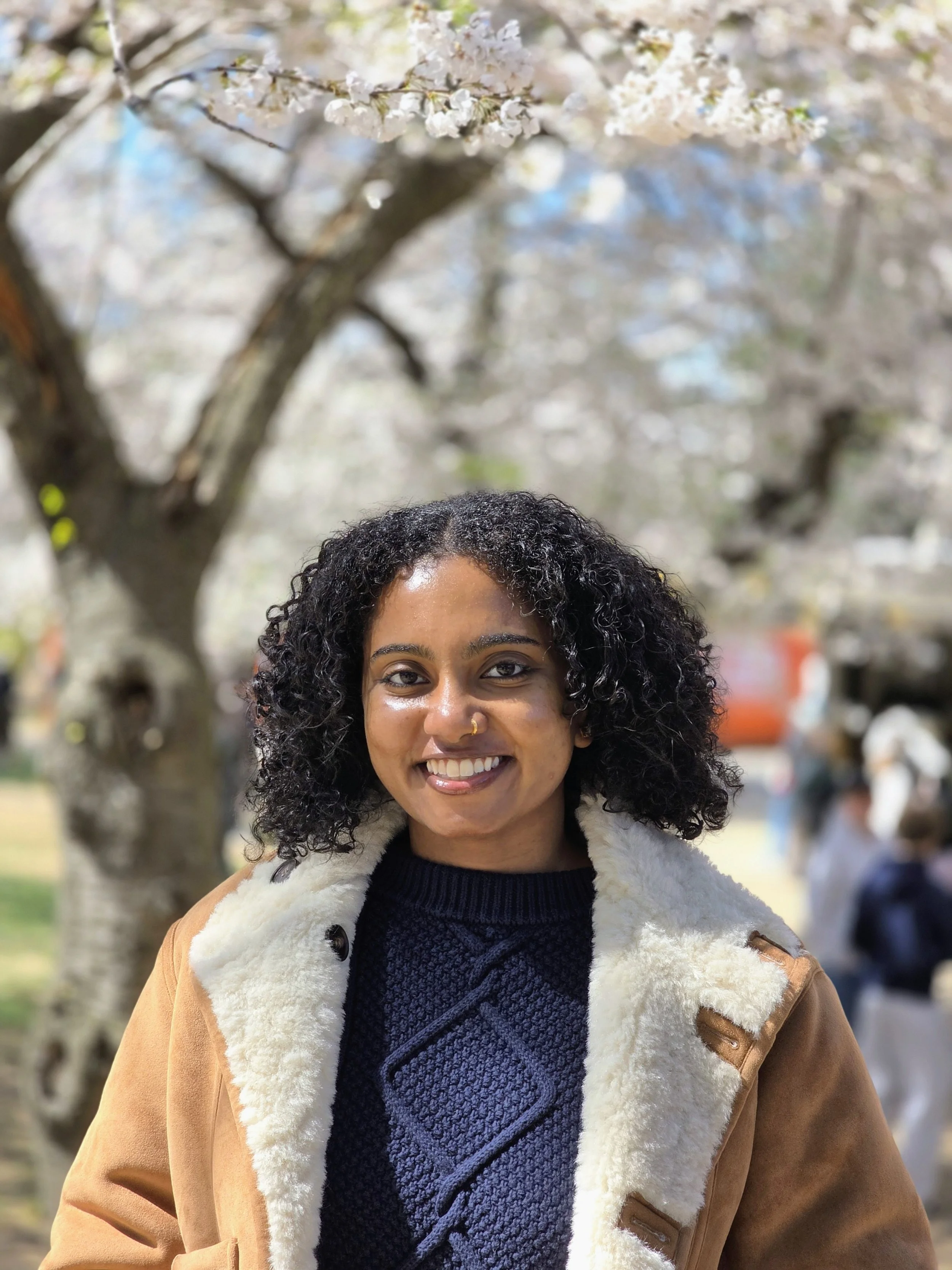 Sarya smiling underneath the Cherry Blossom's in DC.