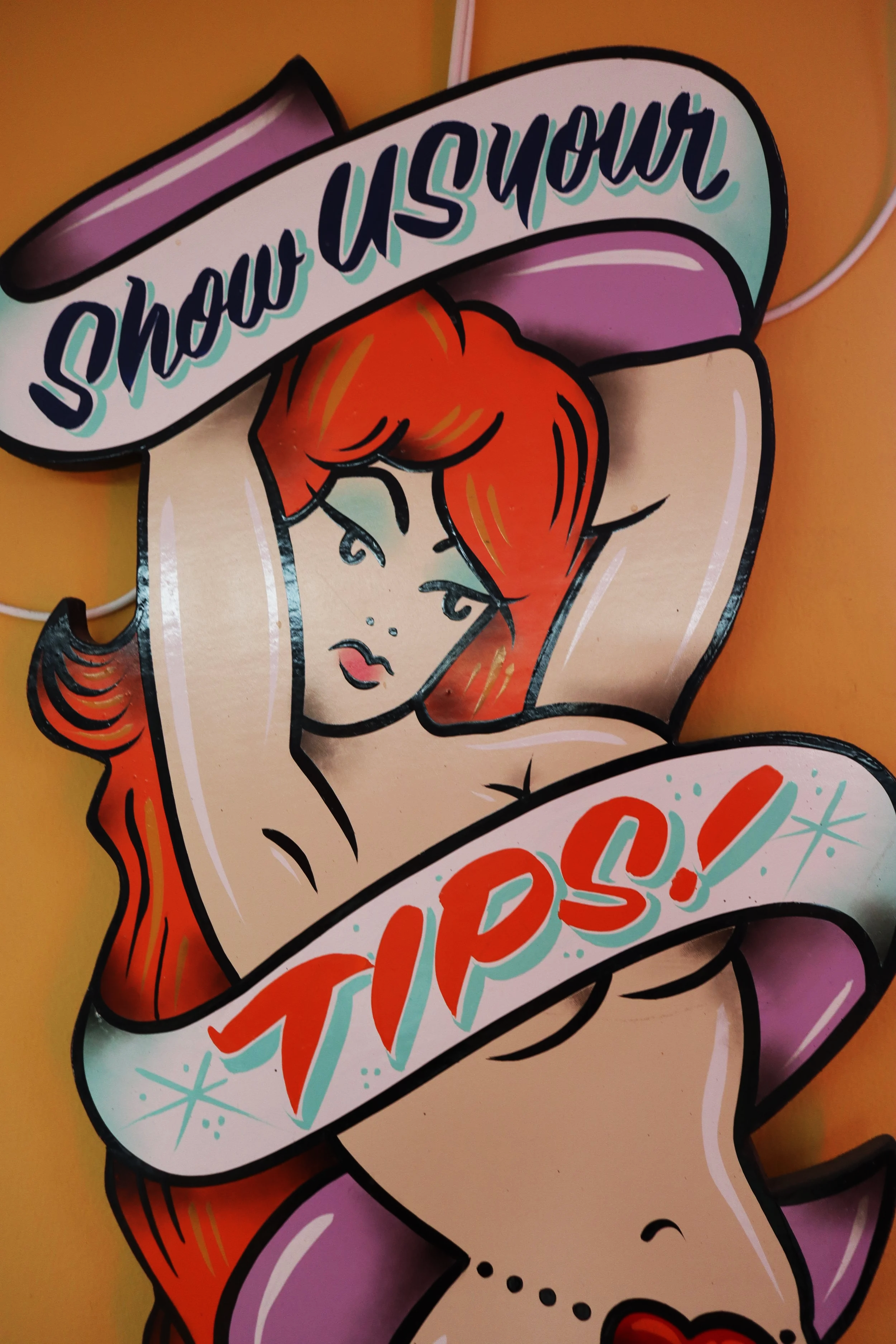 Colourful, illustrated sign featuring a cartoon woman with red hair and closed eyes. The text on the sticker says 'show your' on a banner across her forehead, and 'tips!' in playful, bright letters below.