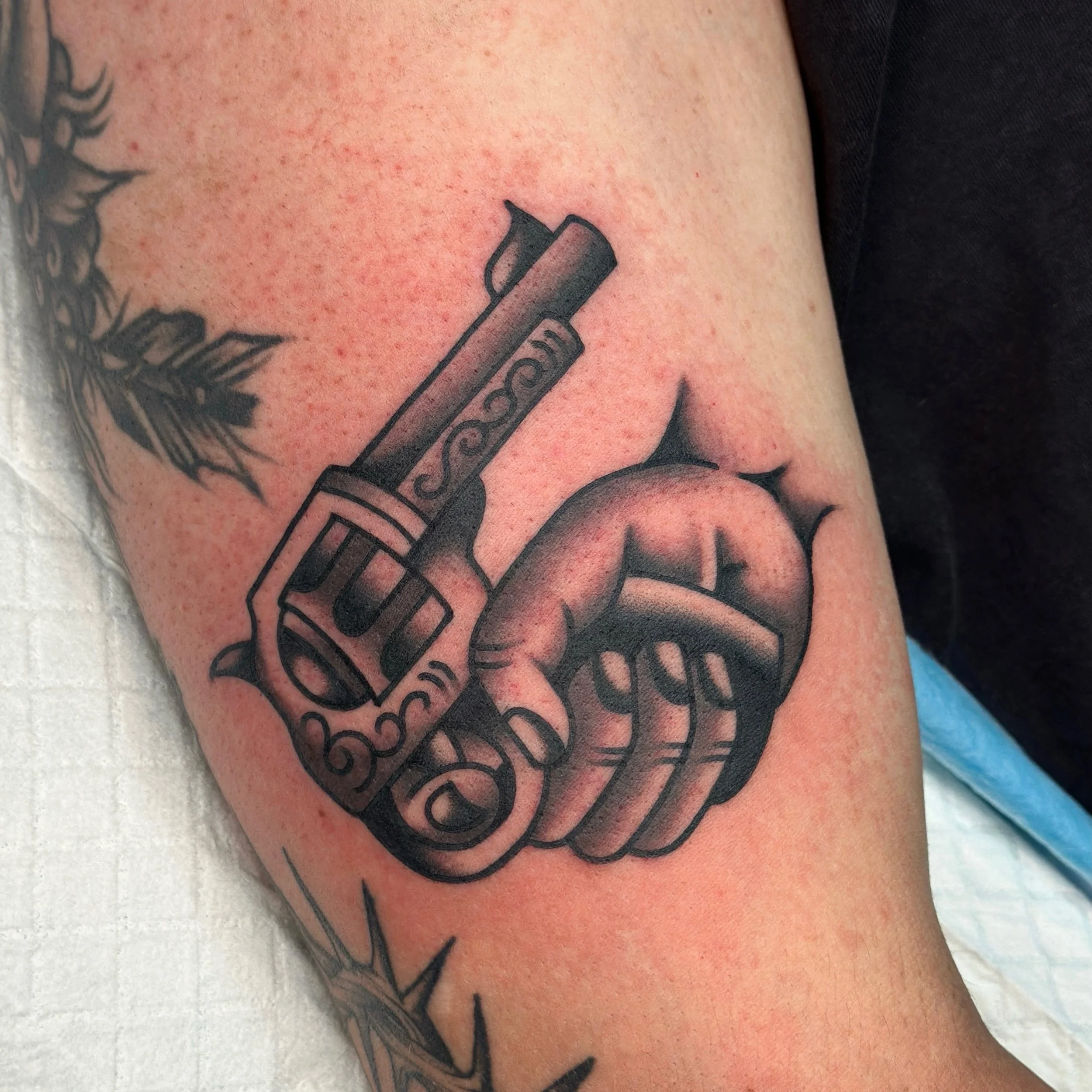 Close-up of a tattoo featuring a gun pointing back on a person's skin.