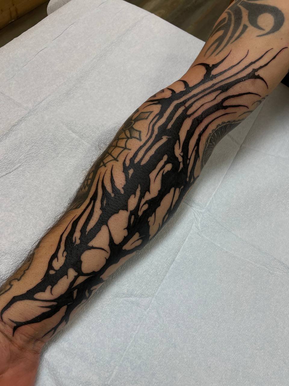 Tattoo of a tree with many branches covering the lower arm and wrist.