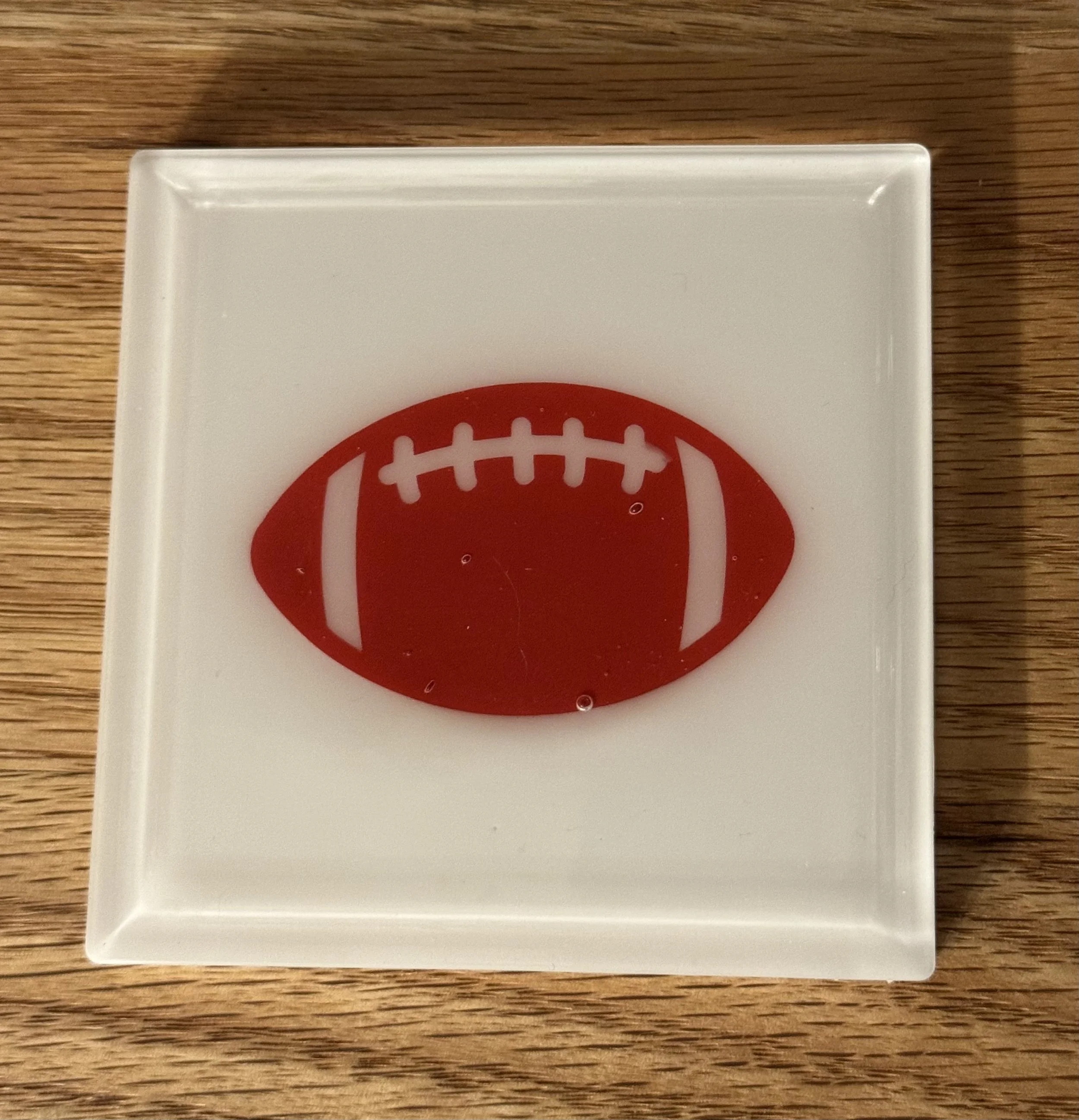Close-up of a white card with a red sports ball graphic, placed on a wooden surface.