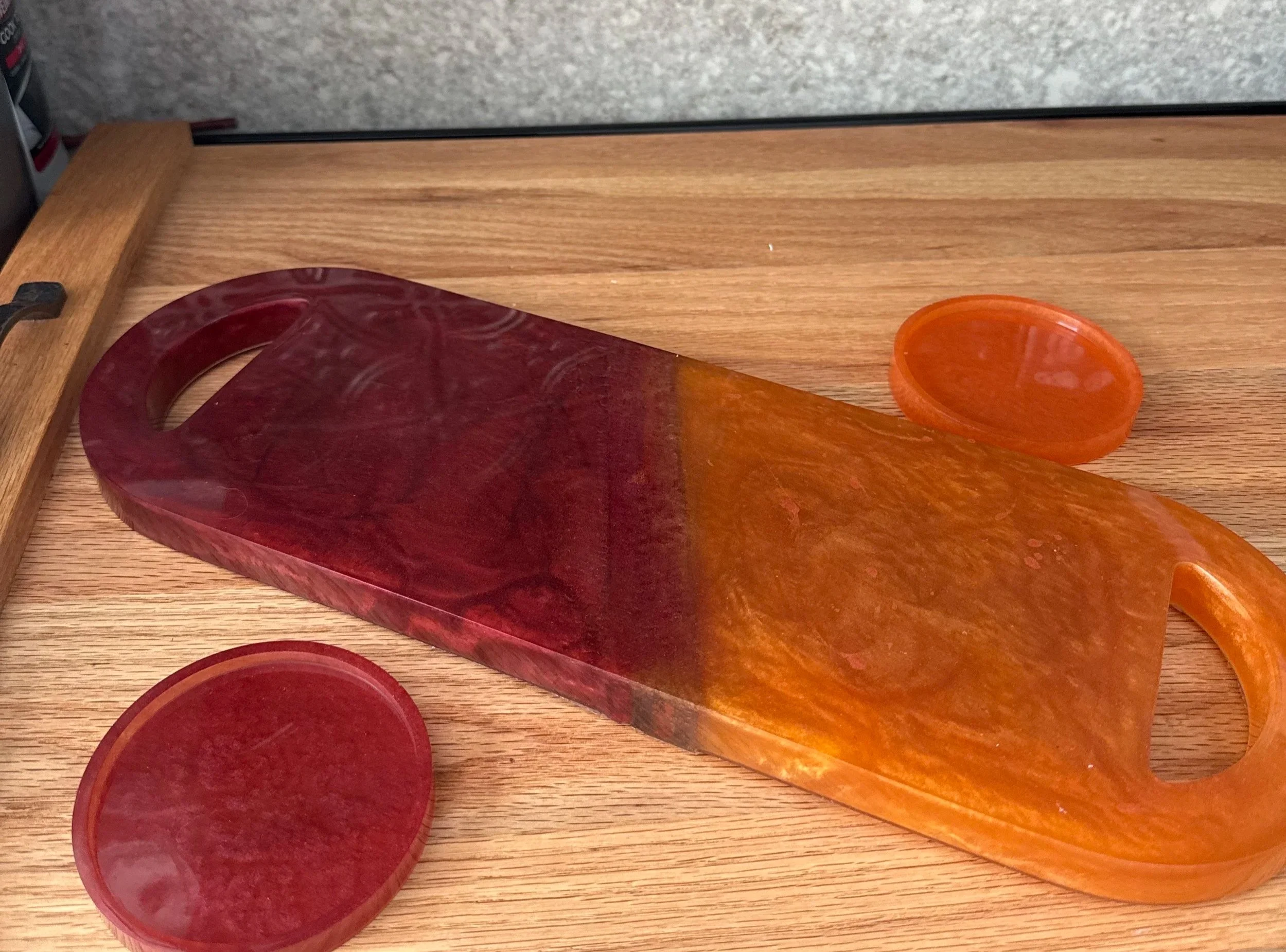 Colorful bowls and a decorative glass cutting board on a wooden surface.