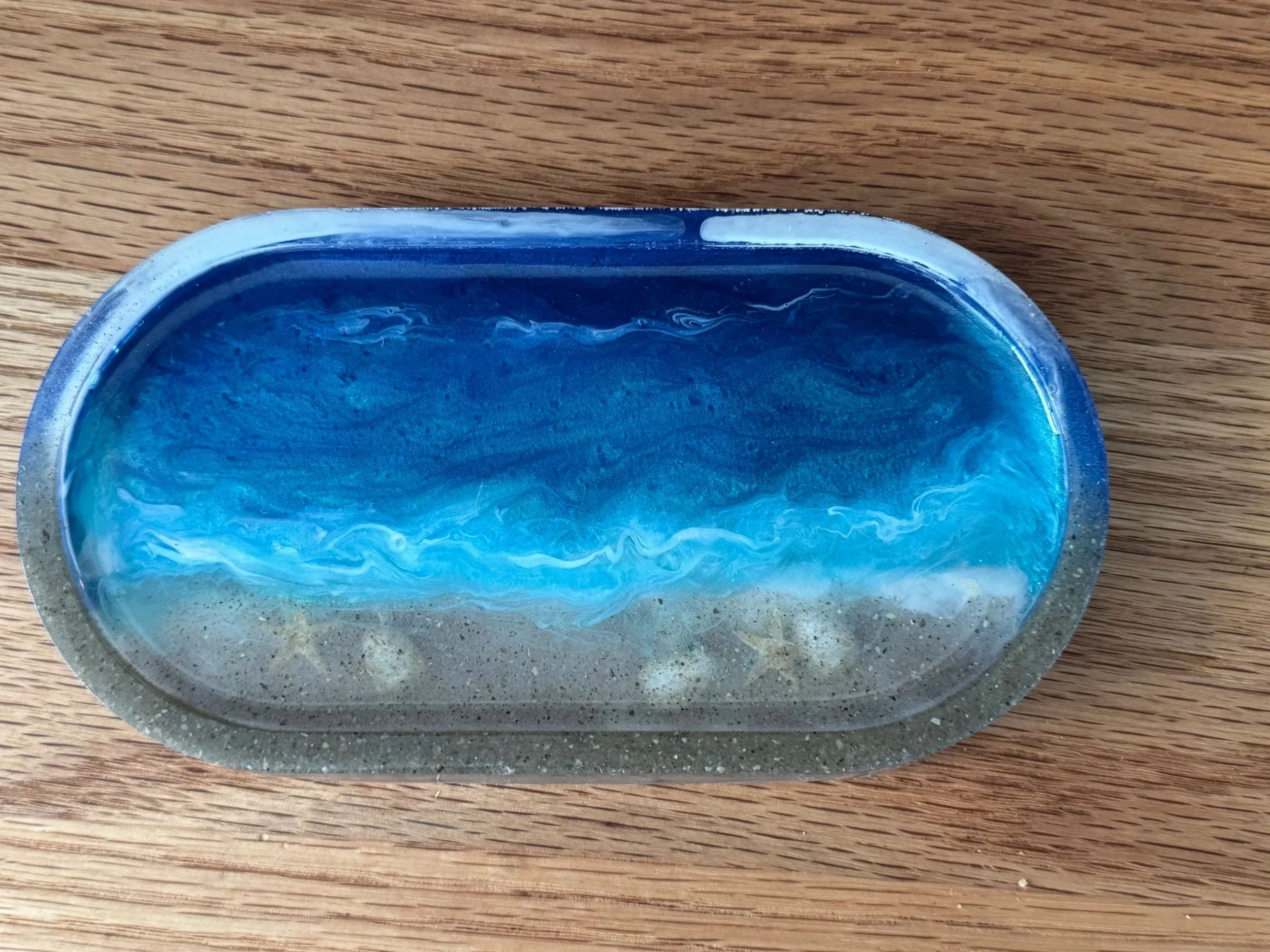 A partially visible blue soap bar in a metal container on a wooden surface.