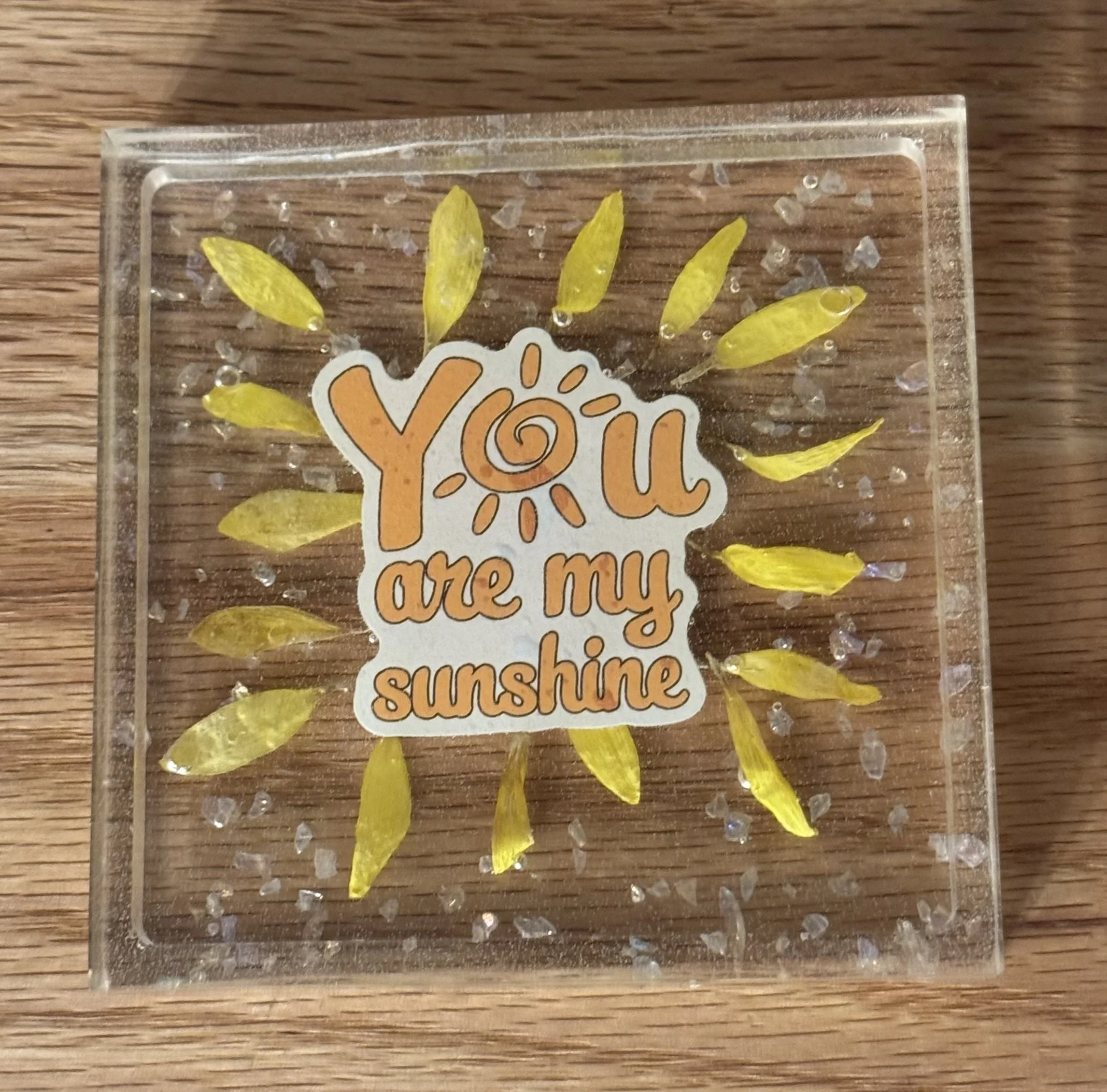 An inspirational coaster with a favorite phrase and flower petals and sparkles