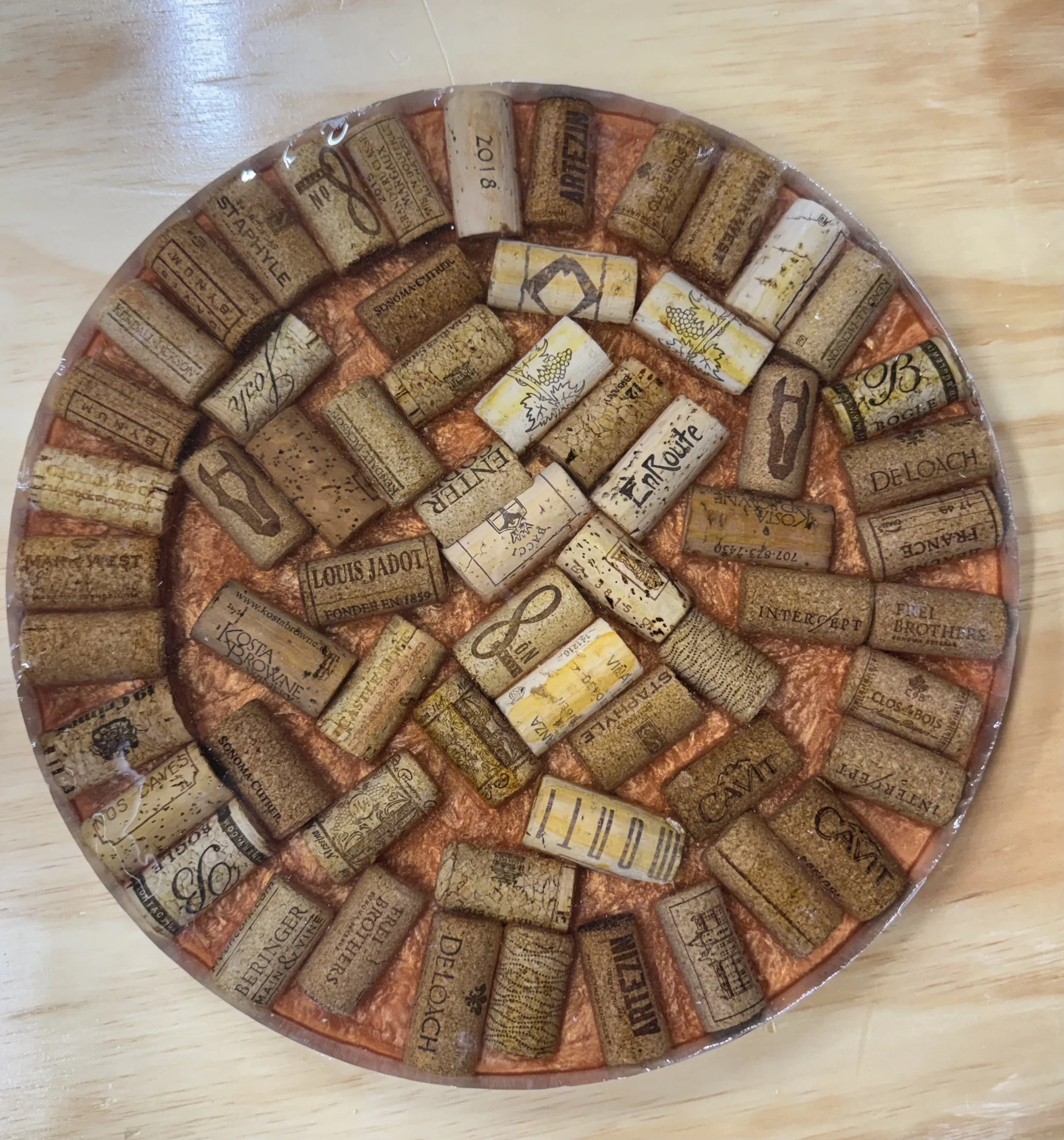 A round serving tray filled with wine corks arranged in concentric circles on a wooden surface.