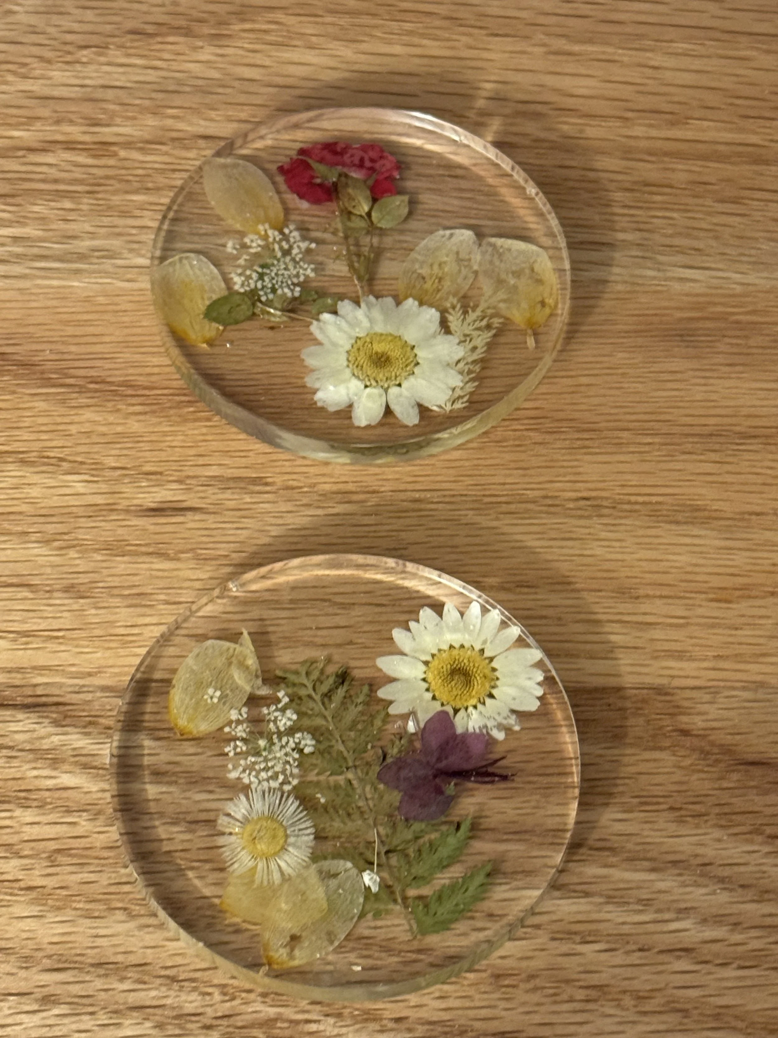 Two clear glass plates with pressed flowers and lemon slices on a wooden surface.