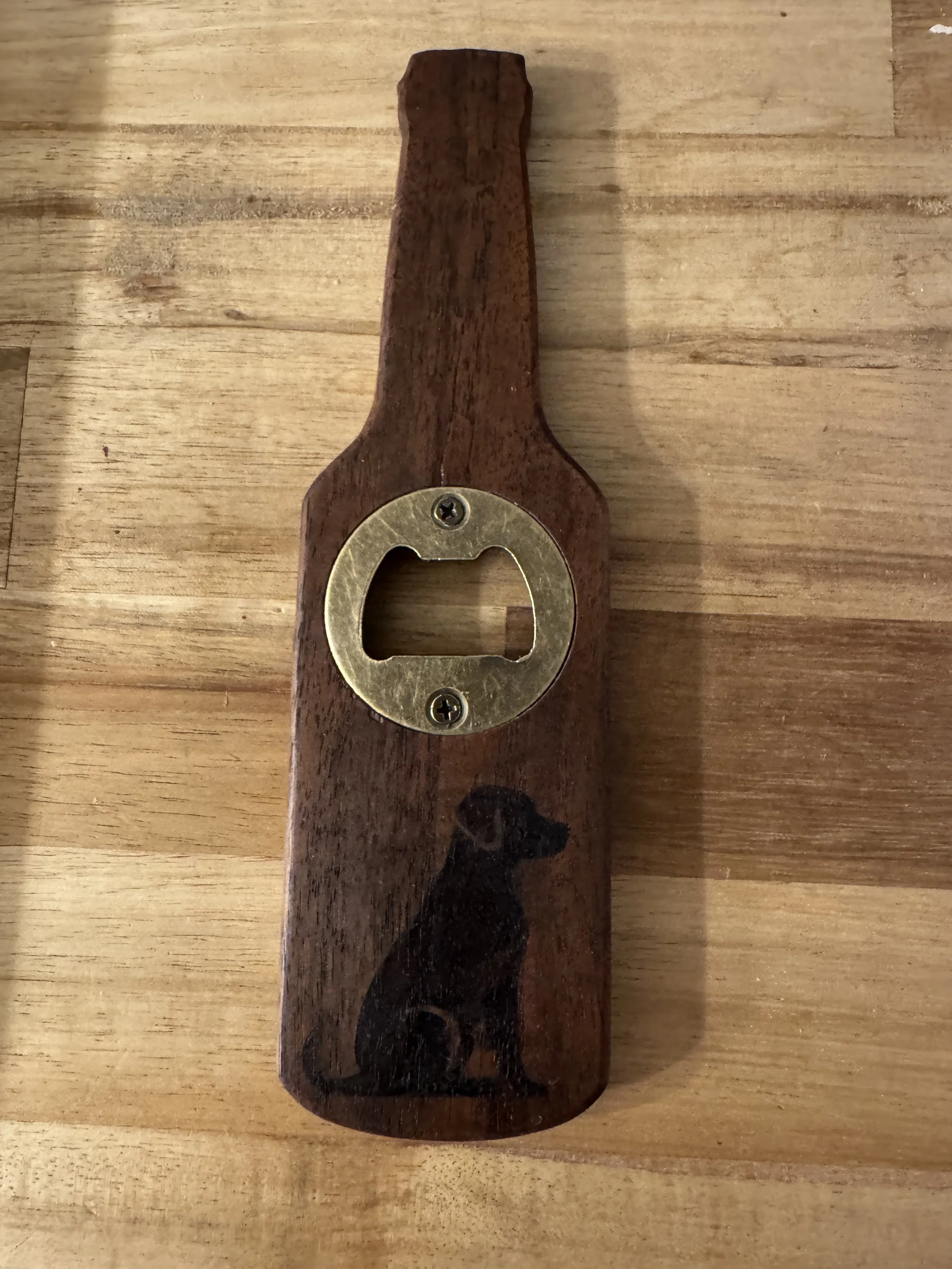 A bottle opener attached to a wooden handle with USA wood burned on the surface.