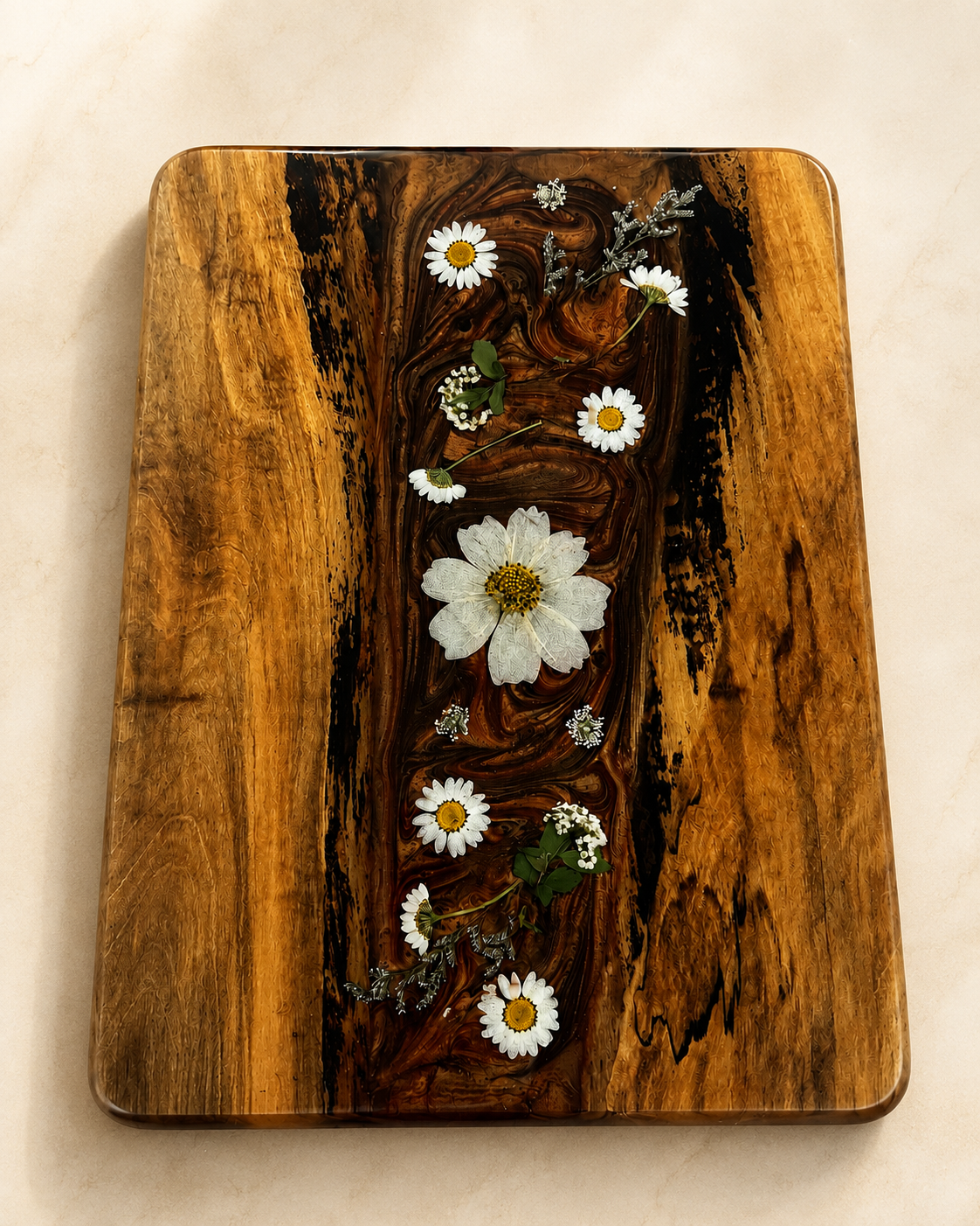 Decorative wooden tray with pressed flowers and small white daisies arranged on top.