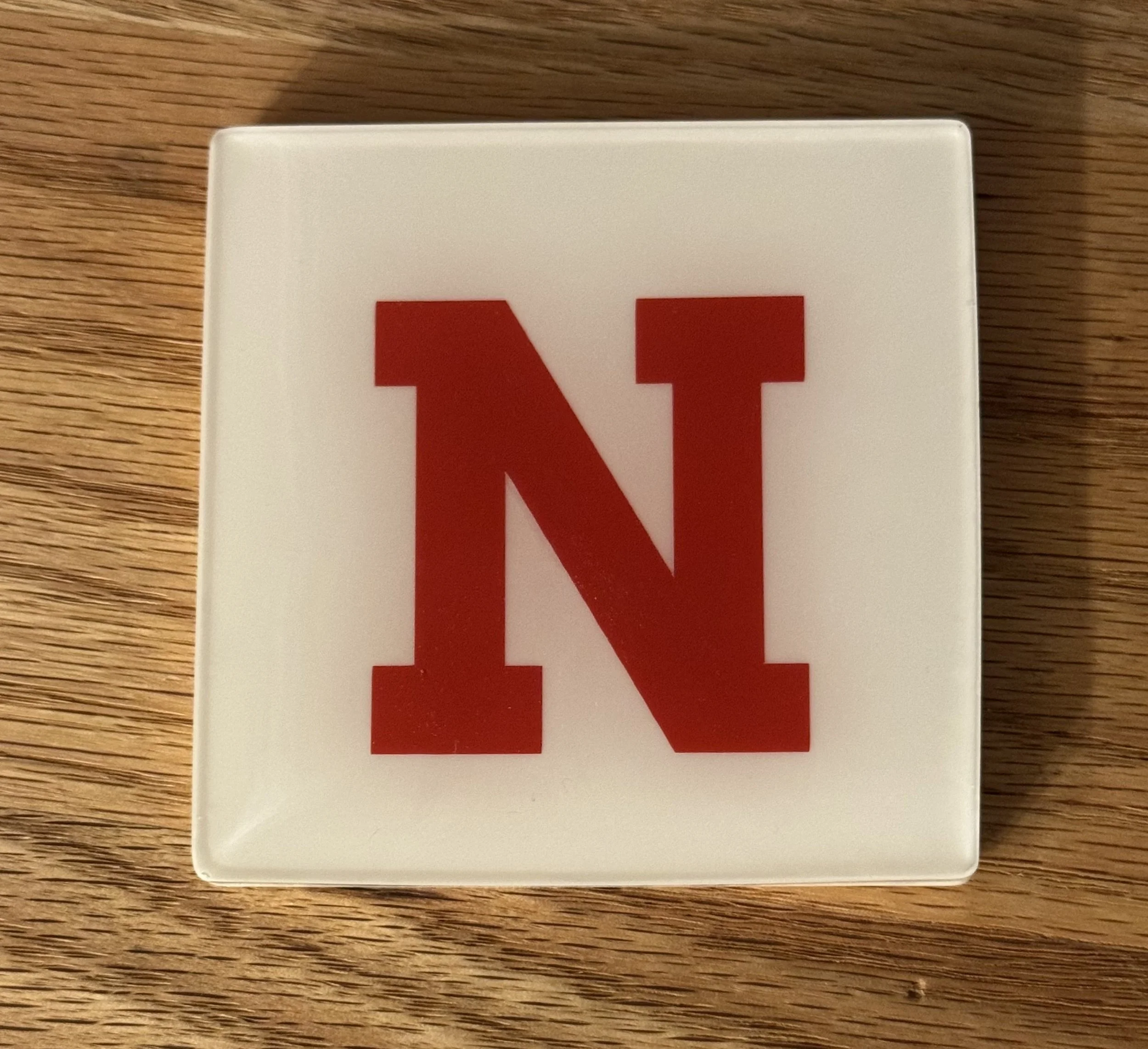 Close-up of a white device with a partial red letter "N" on a wooden surface.