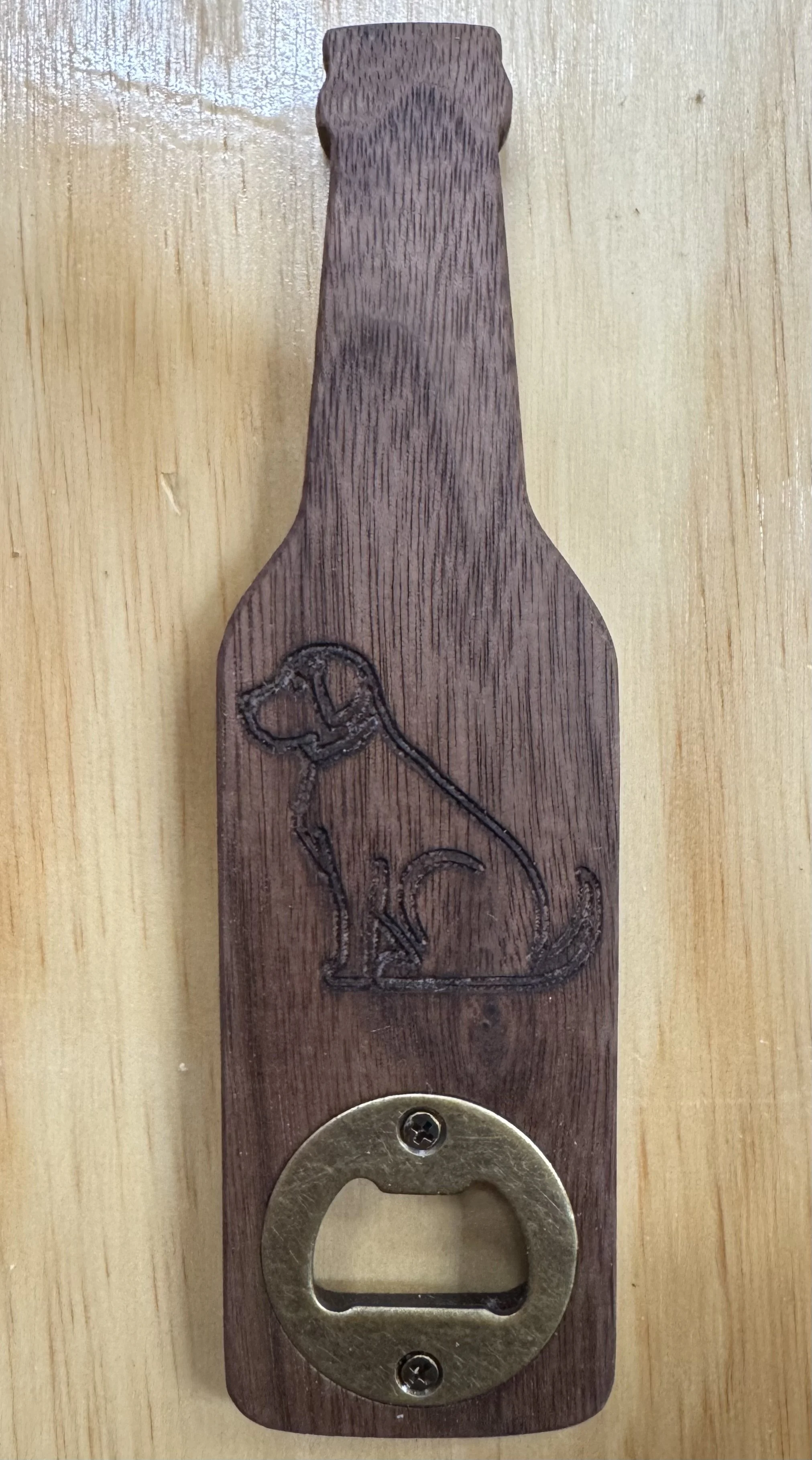 A wooden bottle opener with a engraved picture of a dog.