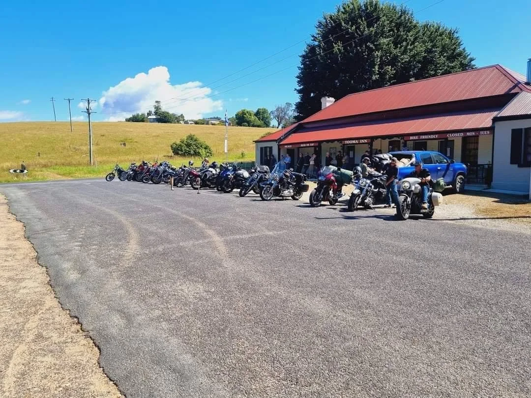Motorcycles parked outside a restaurant with a red roof on a sunny day, with people gathered near the bikes.