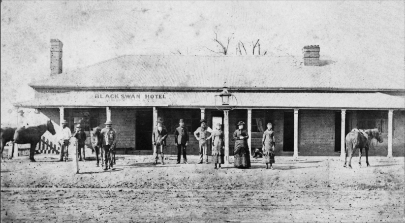 A black-and-white historical photo of the Black Swan Hotel, featuring a group of people and horses in front of the building.