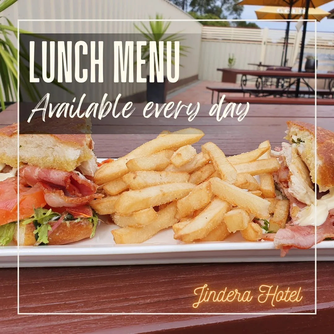 A lunch plate with sandwich halves filled with meats, vegetables, and toppings, accompanied by a side of French fries on an outdoor patio table.
