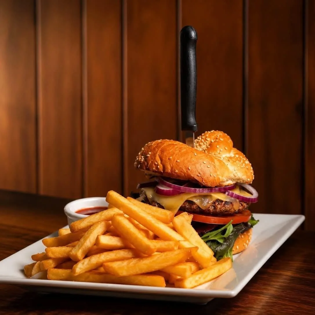 A cheeseburger with lettuce, tomato, onion, cheese, and a beef patty served with a side of French fries and ketchup.