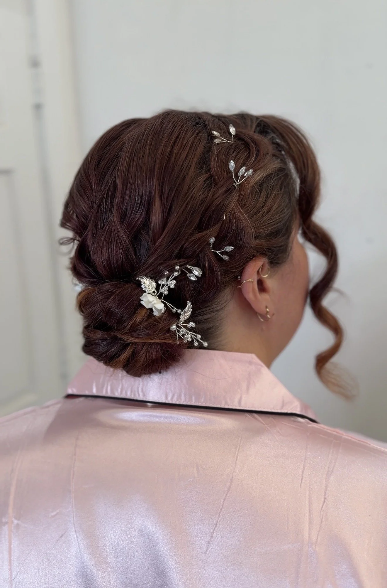 A bridesmaid with brown hair styled in an elegant updo adorned with decorative silver and white hair accessories.