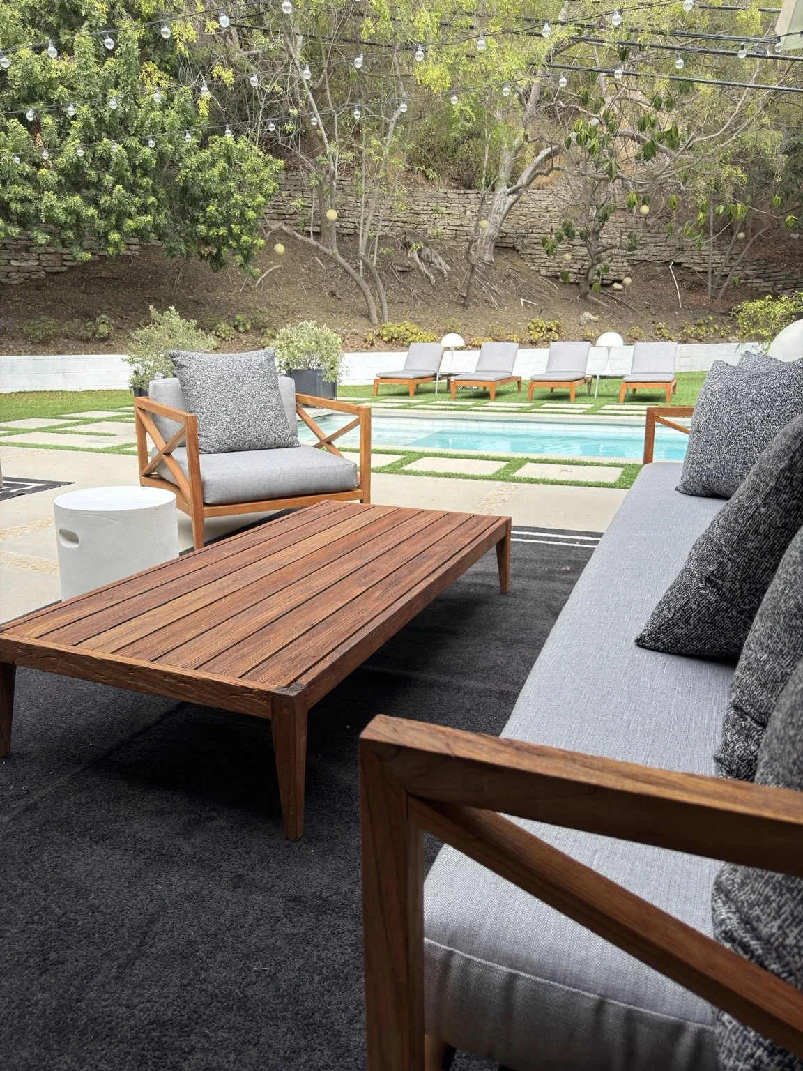 Restored teak sofa and coffee table overlooking a backyard pool