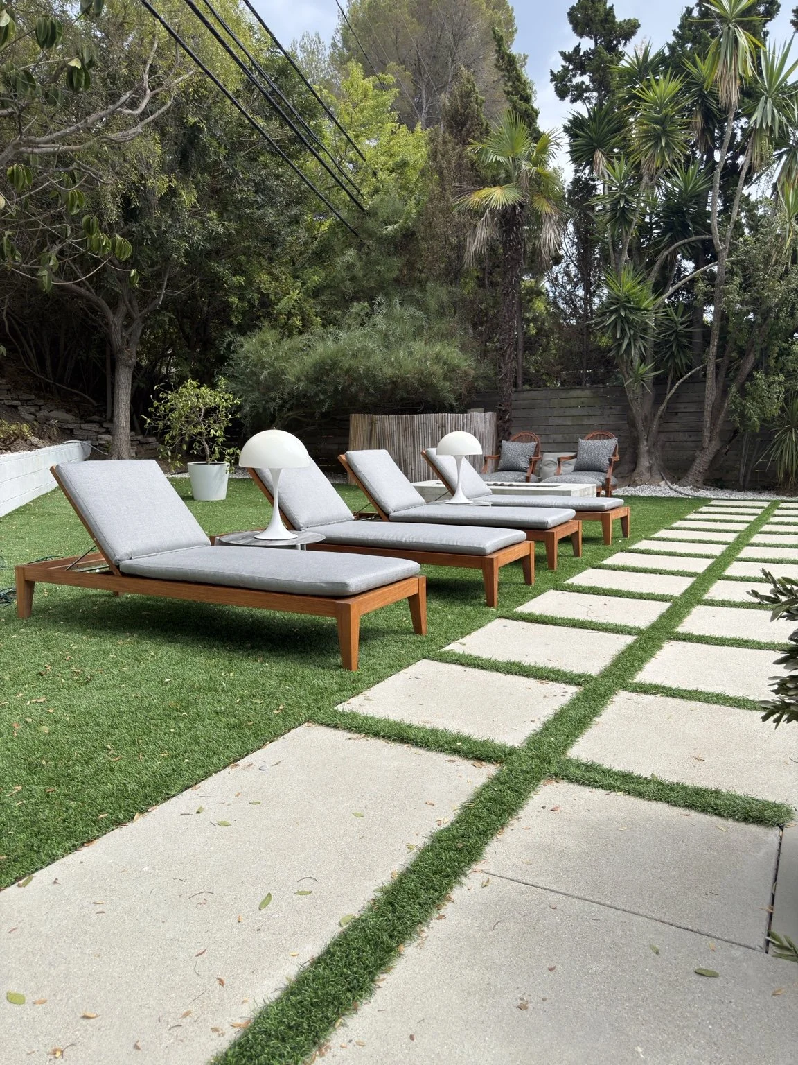 Restored teak chaise lounges with new gray cushions in an outdoor living area