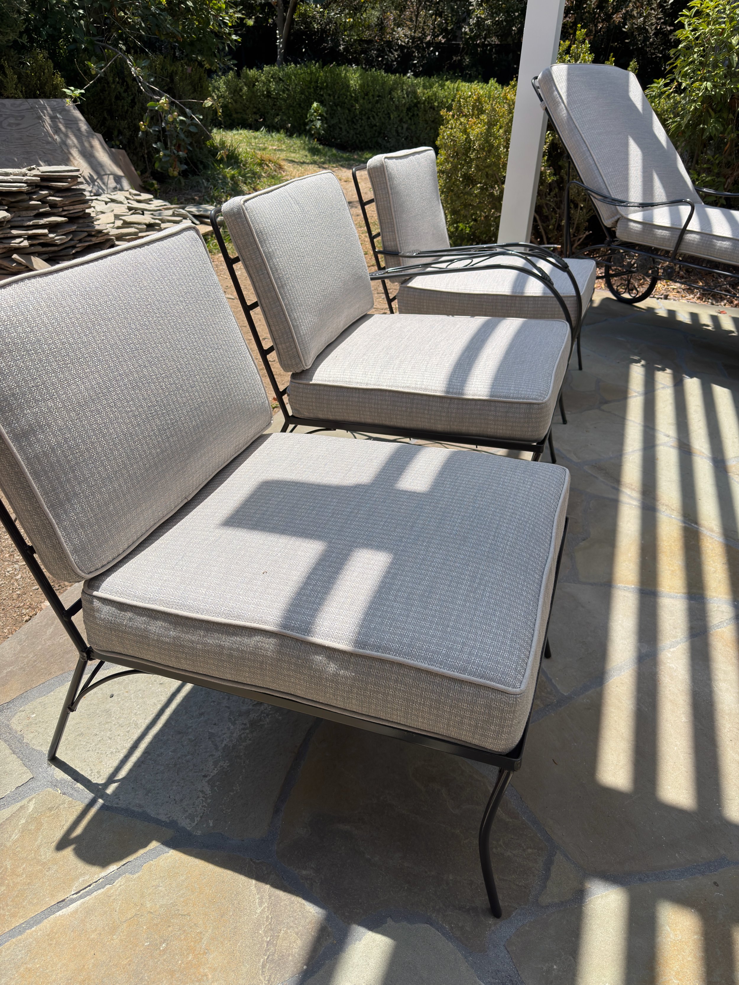 Restored black metal patio seating fitted with clean custom gray outdoor cushions.