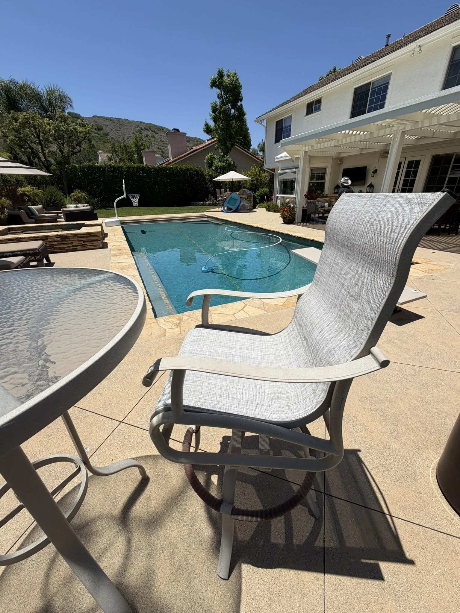 High-back patio chair professionally restored with new sling fabric beside a swimming pool.