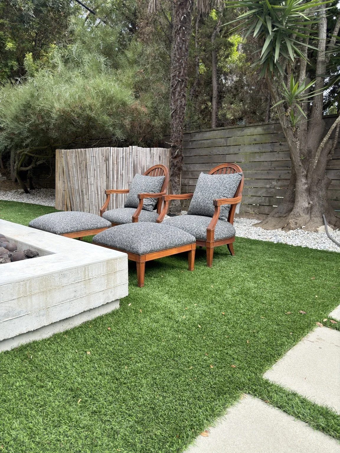 Restored teak patio chairs with patterned cushions beside an outdoor fire pit