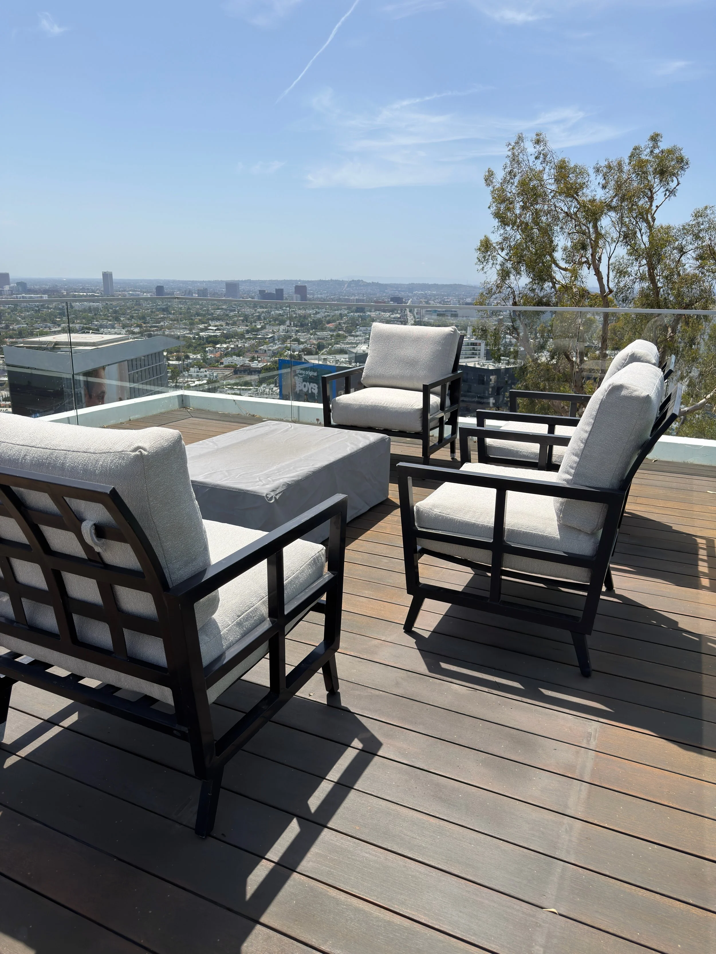 Roof terrace with outdoor seating and a view of the city skyline and hills, under a partly cloudy sky.