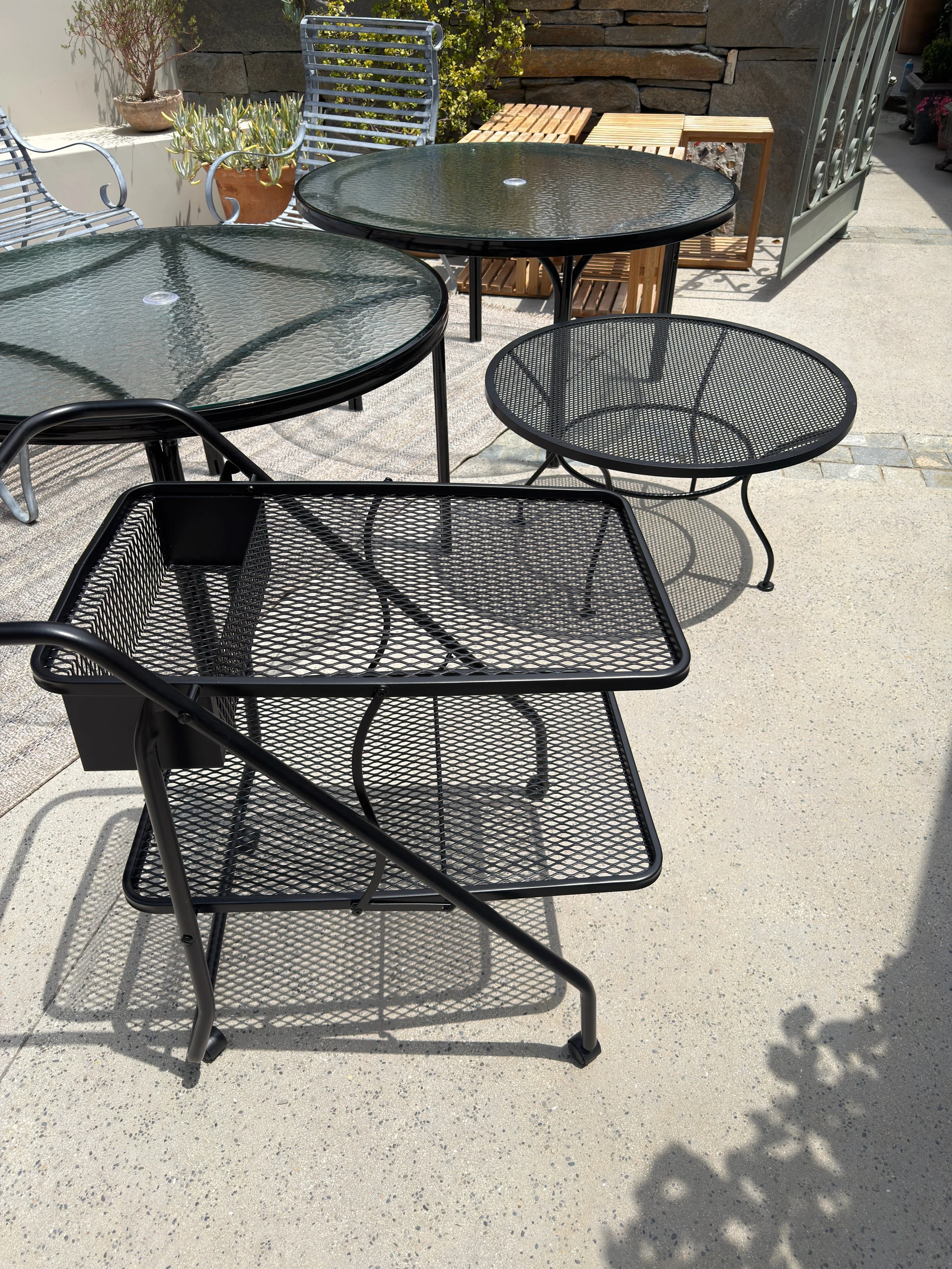 Metal outdoor patio chairs and tables professionally refinished with a durable black powder coated finish to restore worn patio furniture