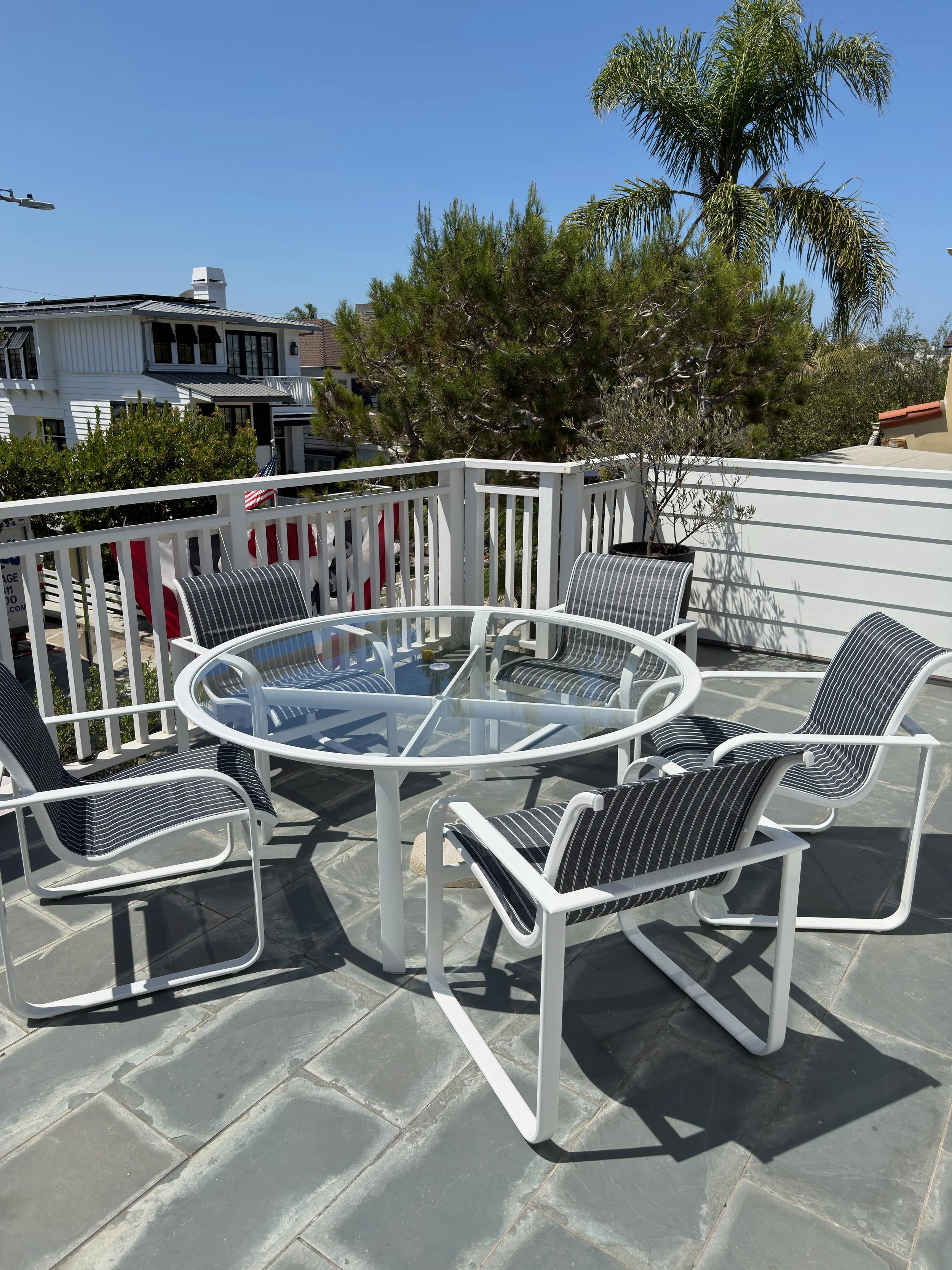 Restored white patio dining set with black-and-white sling seating on a sunny Southern California patio.