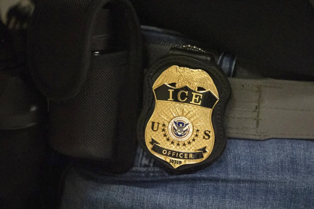A badge clipped to a utility belt officially marking its carrier as an agent of the Bureau of Immigration and Customs Enforcement