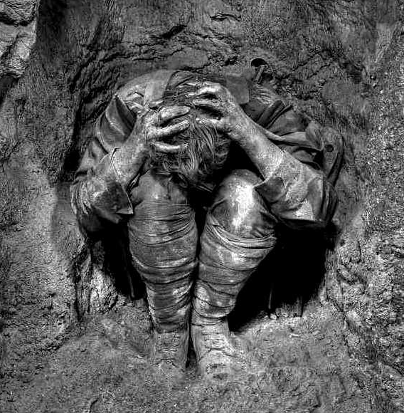 Shell shocked soldier cradles his head in fetal position as he takes cover inside a trench hole.