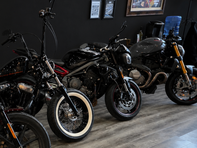 Three black motorcycles indoors on a wooden floor. Ducati, Triumph, Harley, CF moto, honda