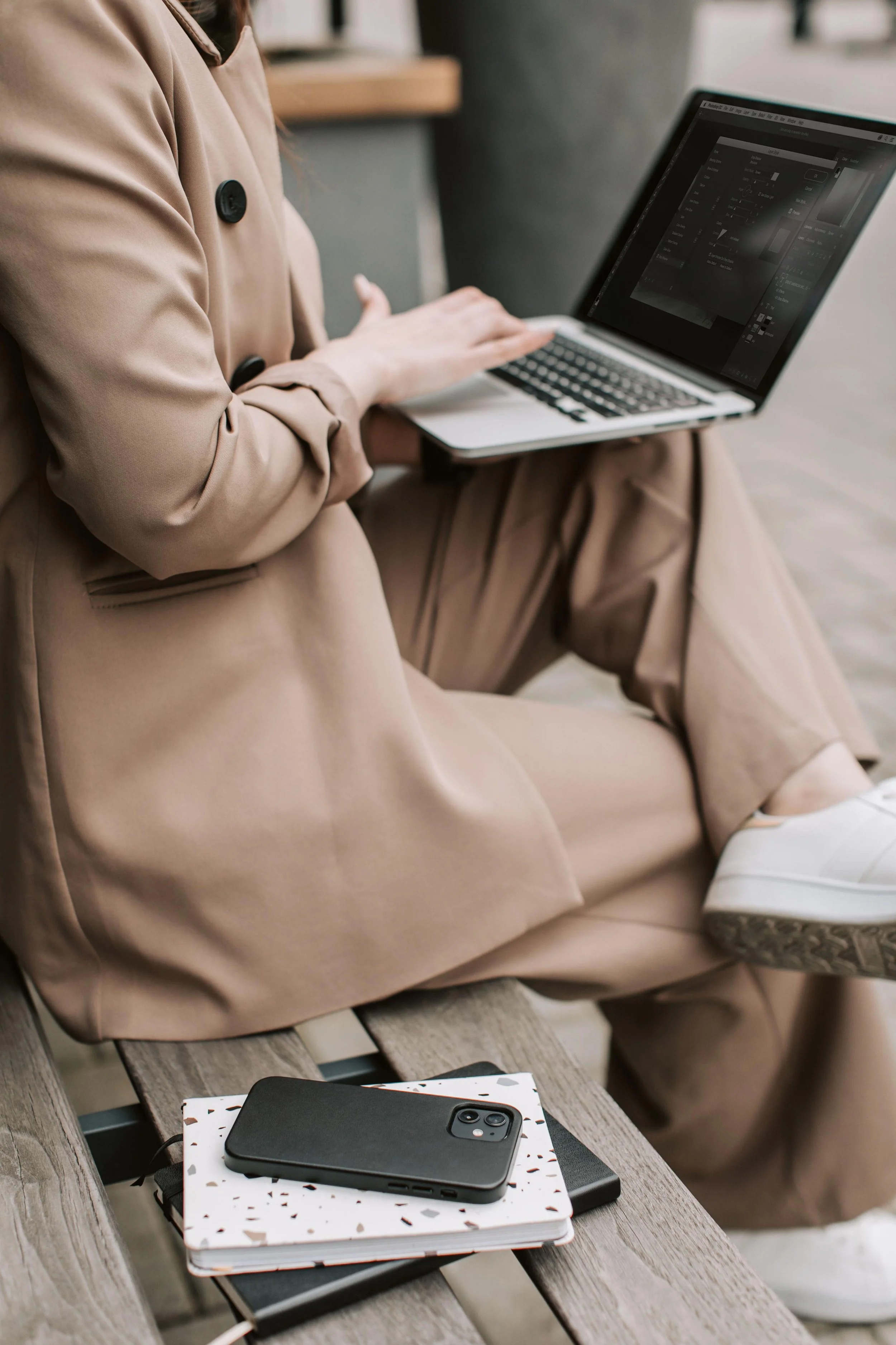 A person sitting on a wooden bench using a laptop.