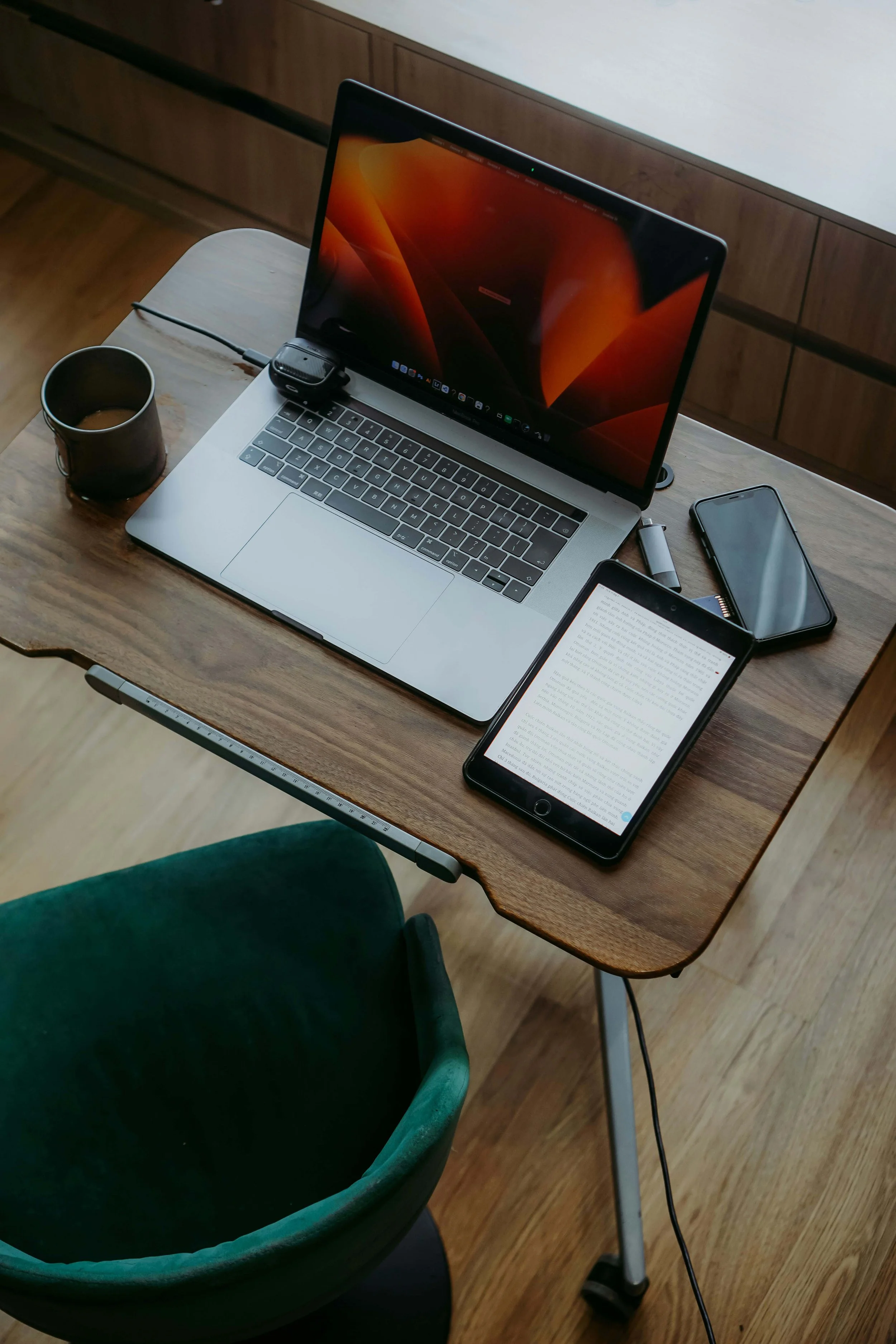 Bird's eye view of a wooden desk with a laptop and coffee