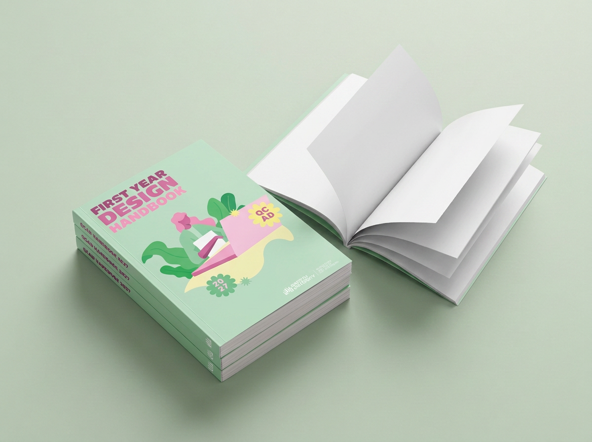 Open book with blank white pages and a closed book titled "First Year Design Handbook" with pastel green, pink, and purple cover, featuring an illustration of a person reading surrounded by plants.