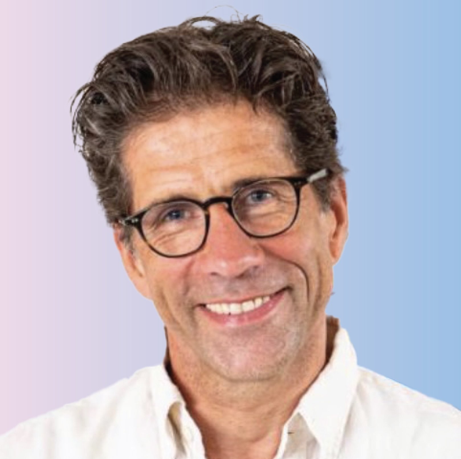 A middle-aged man with dark, curly hair, glasses, and a friendly smile, wearing a white collared shirt, in front of a light blue background.