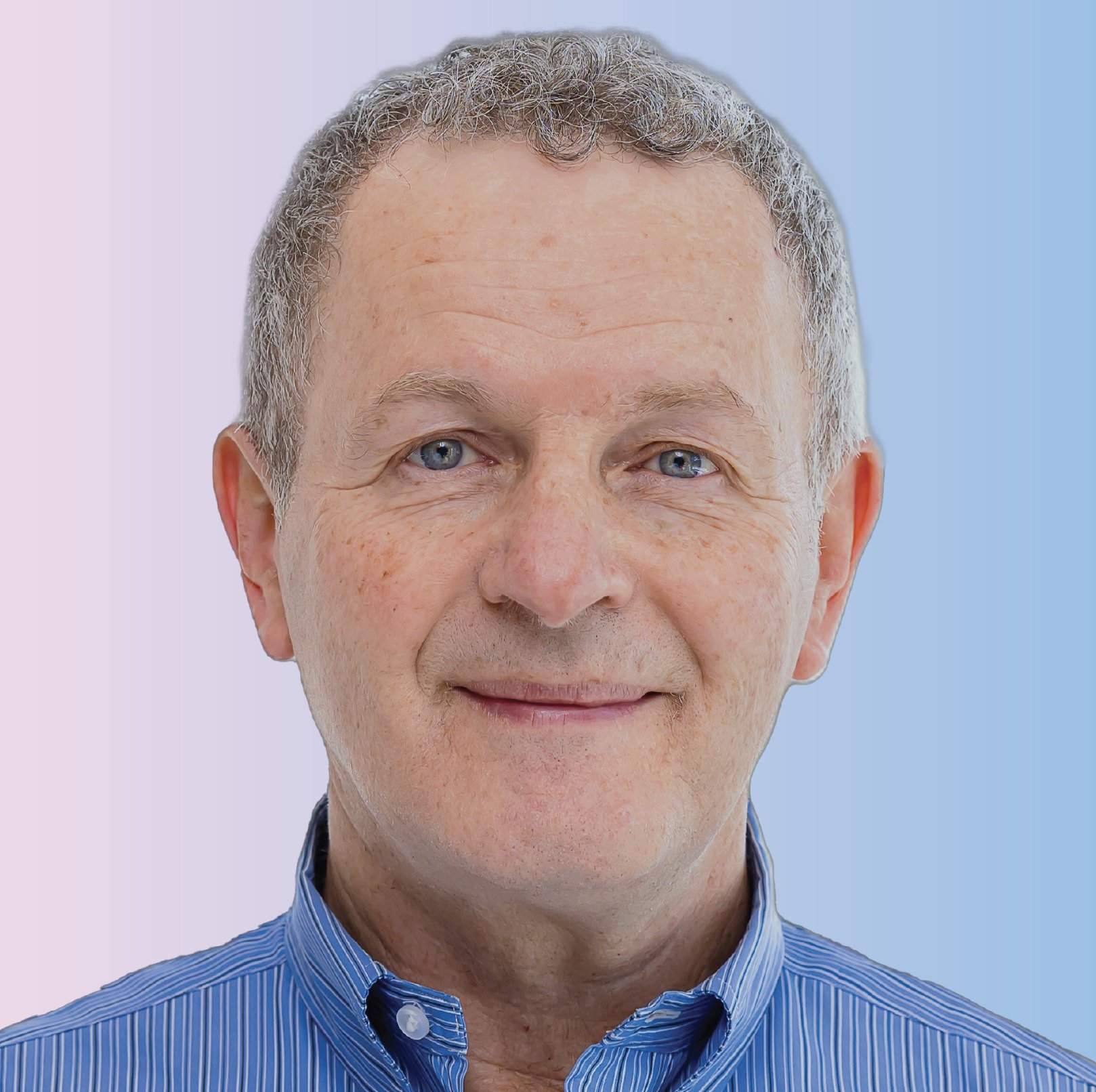 Close-up portrait of a smiling middle-aged man with short gray hair, wearing a blue striped shirt, against a background with light purple to light blue gradient.