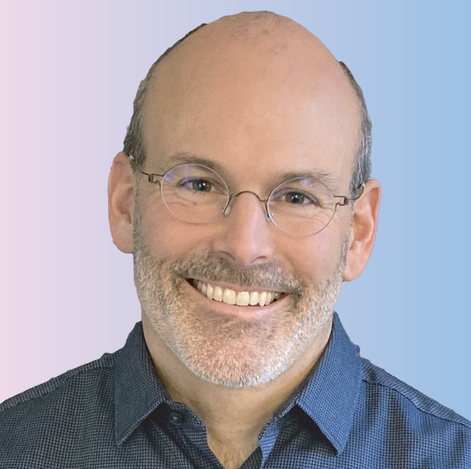 Close-up of a smiling middle-aged man with glasses, short hair, beard, and a blue collared shirt, against a light blue background.