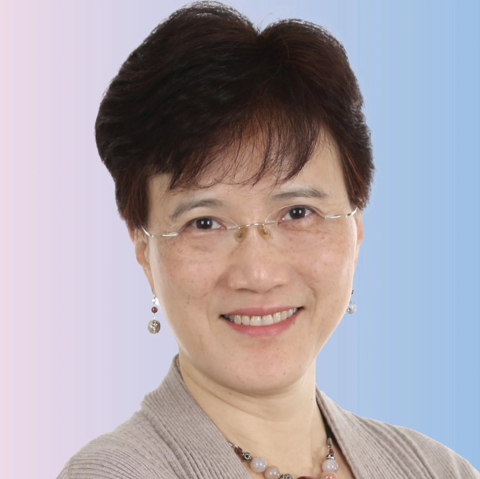 A portrait of a smiling Asian woman with short dark hair, wearing glasses, earrings, a necklace, and a beige top, against a split pink and blue background.